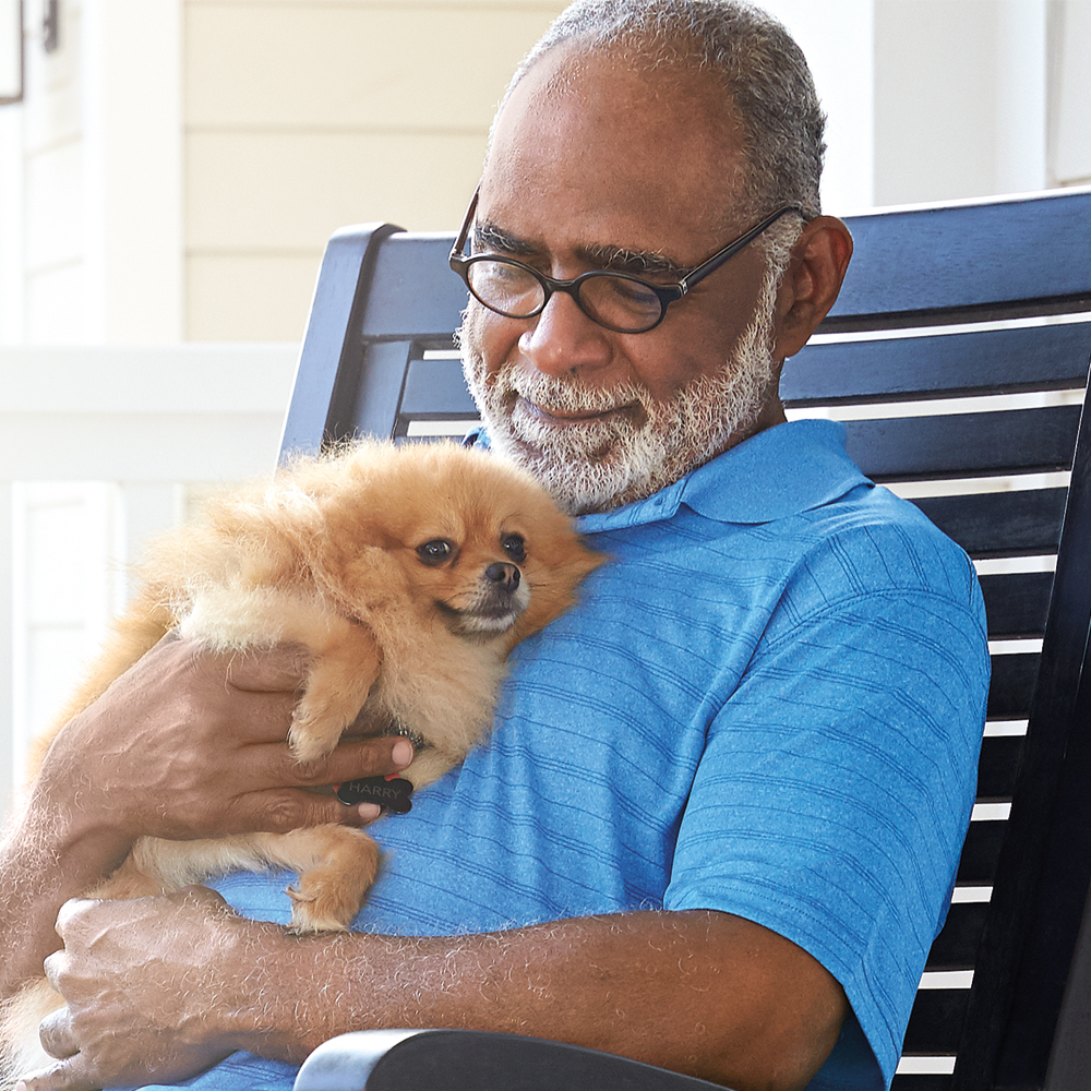 Older man in a chair while holding a dog