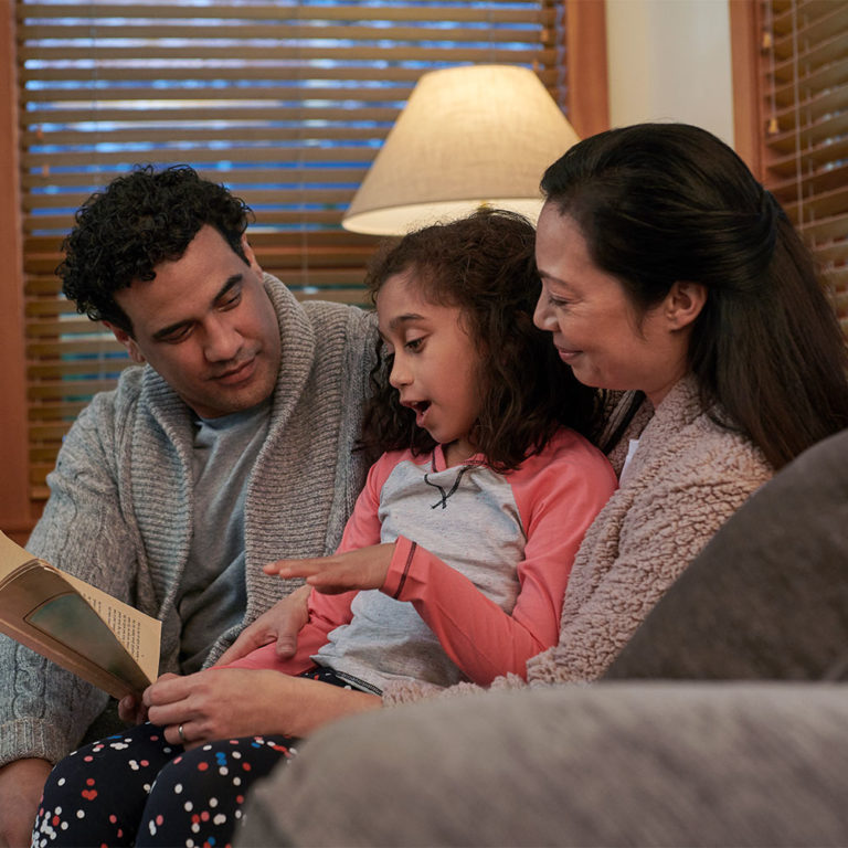 Family sitting on couch reading a book