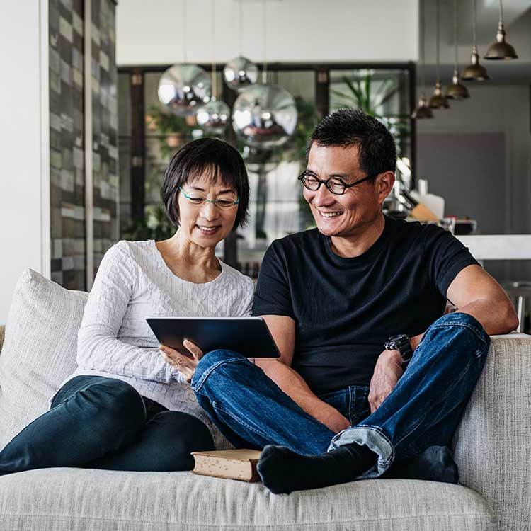 Man and woman on couch looking at a tablet